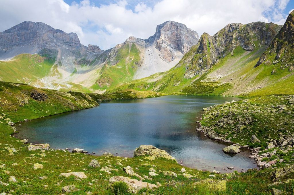 Glacier Lakes Grow as Alpine Valleys Warm Faster A turquoise glacier lake nestled in a green mountain valley beneath rocky peaks.