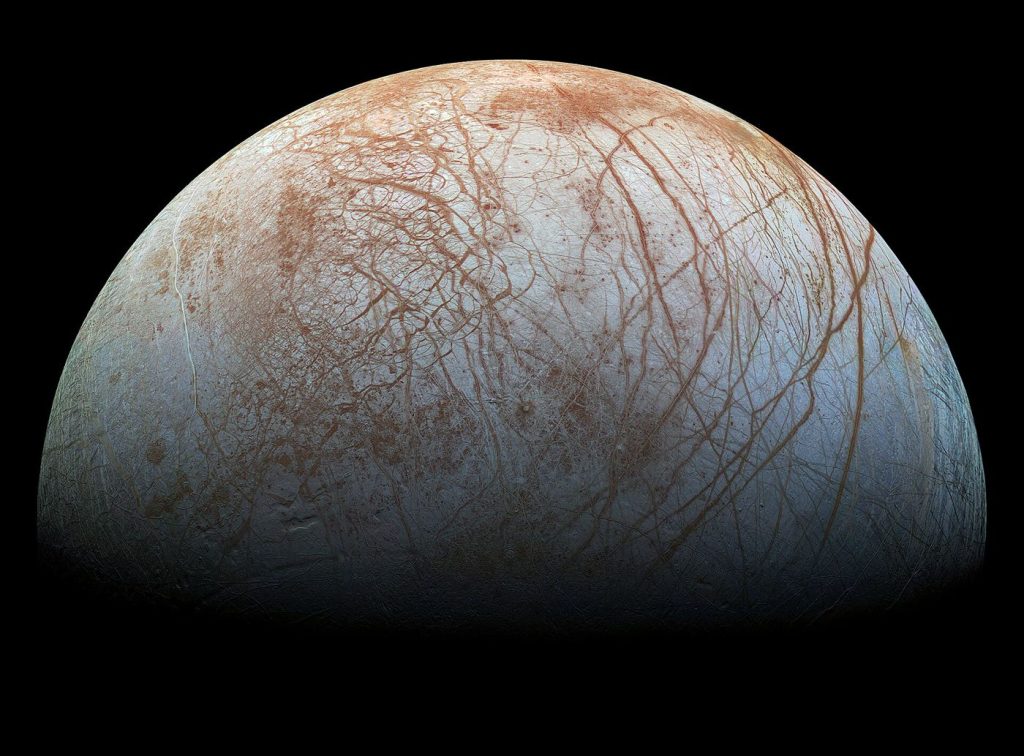 Europa’s Ice Shell Holds Clues to a Hidden Ocean Jupiter's icy moon Europa showing cracked white and rust-coloured ice lines against dark space.